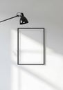 Black framed blank picture on white wall with overhead lamp image Royalty Free Stock Photo