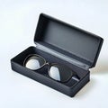 A pair of black framed glasses resting inside of a black protective case on a white surface studio shot Royalty Free Stock Photo