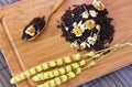 Black friable tea with sage and chamomile. On wooden spoon on tr