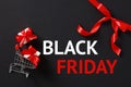 Black Friday banner design. Shopping card, gift boxes, red ribbon bow on black background Royalty Free Stock Photo