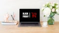 Black friday concept. Laptop screen with shopping card and sign `Black friday` on wooden desk