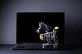 Black friday concept. A laptop with a yellow trolley with a black gift, on a black background Royalty Free Stock Photo