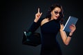 Black Friday and Cyber Monday sale concept for shop. Shopping woman holding bag and pointing on tablet isolated on dark Royalty Free Stock Photo