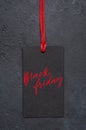 Black Friday - handwritten inscription on the tag. The concept of holiday sales. Dark concrete background