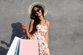 Black Friday, Happy beautiful young woman in black sunglasses with shopping bags, outdoors on gray city wall background Royalty Free Stock Photo