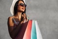 Black Friday, Happy beautiful young woman in black sunglasses with shopping bags, outdoors on gray city wall background Royalty Free Stock Photo