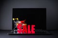 Black Friday Sale concept, yellow trolley with gift, black background with laptop Royalty Free Stock Photo