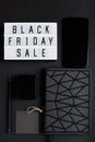 Black Friday sale. Smartphone and accessories on dark background. Monochromatic flatlay, online shopping concept.