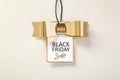 Black friday sale tag with gold bow on beige background Royalty Free Stock Photo