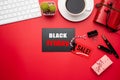 Black Friday Sale text on a red and black tag with coffee cup, plant table, gift box Earphone and mouse keyboard on red background Royalty Free Stock Photo