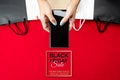 Black friday sale, woman hand online shopping on smartphone with shopping bag on red background Royalty Free Stock Photo