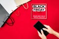 Black friday sale, woman hand online shopping on smartphone with shopping bag on red background Royalty Free Stock Photo