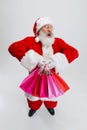 Full-length portrait of senior man wearing Santa Claus costume, holding many shopping packages isolated over white Royalty Free Stock Photo