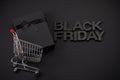 Black Friday Shopping. Black Friday theme with gift box and shopping cart on dark background. Royalty Free Stock Photo