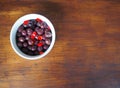 Black fried olives with red peppers slices in a bowl on a rustic wooden plank. Italian food specialty with copy space.