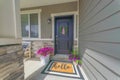 Black front door of a house with wreath and potted flowers at the front Royalty Free Stock Photo