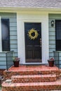 a black front door and a wreath on a revently renovated blue small cottage style house Royalty Free Stock Photo