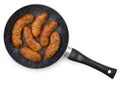 Black frying pan with fried rustic sausages, isolated on a white background, top view Royalty Free Stock Photo
