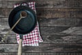 Black frying pan with a wooden spoon on a brown wooden surface Royalty Free Stock Photo