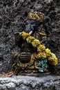 Black Ganesha statue with a wreath of flowers