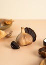 Black garlic bulbs, cloves and peel lie on a beige table. A conceptual composition of fermented black garlic. Healthy nutrition, Royalty Free Stock Photo