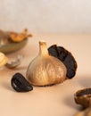 Black garlic bulbs, cloves and peel lie on a beige table. A conceptual composition of fermented black garlic. Healthy nutrition, Royalty Free Stock Photo