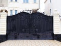Black gates with a wrought-iron pattern of monograms adjoin the white columns of the fence that encloses a private villa