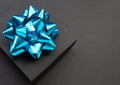 Black gift box on a black background, decorated with a blue bow, creating a romantic atmosphere. Typically used for birt Royalty Free Stock Photo