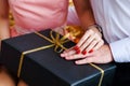 Black gift box with golden bow in hands of couple in love Royalty Free Stock Photo