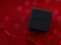 Black gift box is on red heart paper background, top view