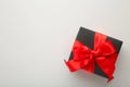 Black gift box with red ribbon and bow on grey background Royalty Free Stock Photo