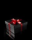 Black gift box with red satin ribbon bow isolated on black Royalty Free Stock Photo