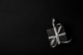 Black gift box with silver ribbon bow on black background. Top view, copy space Royalty Free Stock Photo