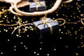 Black gift boxes with gold ribbon pop out from golden bag on shine background. Close up.