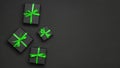Black gift boxes tied with green ribbons on black