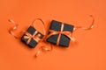 Black gift boxes tied with orange ribbons on an orange background. Royalty Free Stock Photo