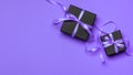 Black gift boxes tied with purple ribbons on a purple background