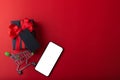 Black gift and red ribbon with black tag on red color background, Black credit card inside small cart and smartphone for shopping. Royalty Free Stock Photo