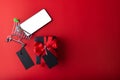 Black gift and red ribbon with black tag on red color background, small cart and smartphone for shopping on red color. 11.11 singl Royalty Free Stock Photo