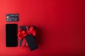 Black gift and red ribbon with black tag on red color background, Black credit card inside small cart and smartphone for shopping. Royalty Free Stock Photo