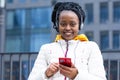 Black girl, african american woman listen music with headphones on mobile phone outdoor. Royalty Free Stock Photo