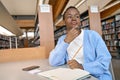 Black girl college student looking away thinking writing essay in library. Royalty Free Stock Photo