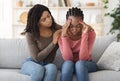 Black girl comforting her sad friend, home interior