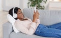 Black girl enjoying listening music on smartphone with wireless headphones at home Royalty Free Stock Photo