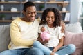 Black girl and father putting coin into piggy bank Royalty Free Stock Photo