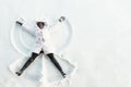 Black girl lies on white forest glade and makes snow angles