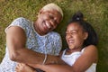 Black girl and grandmother lying on grass, overhead close up