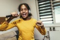 Black girl holding microphon singing karaoke at home, recording songs for contest. Children's lifestyle concept