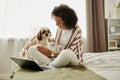 Black girl relaxing at home sitting on bed with cute pet dog Royalty Free Stock Photo