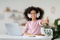 Black girl schooler using laptop and headphones, showing thumb up Royalty Free Stock Photo